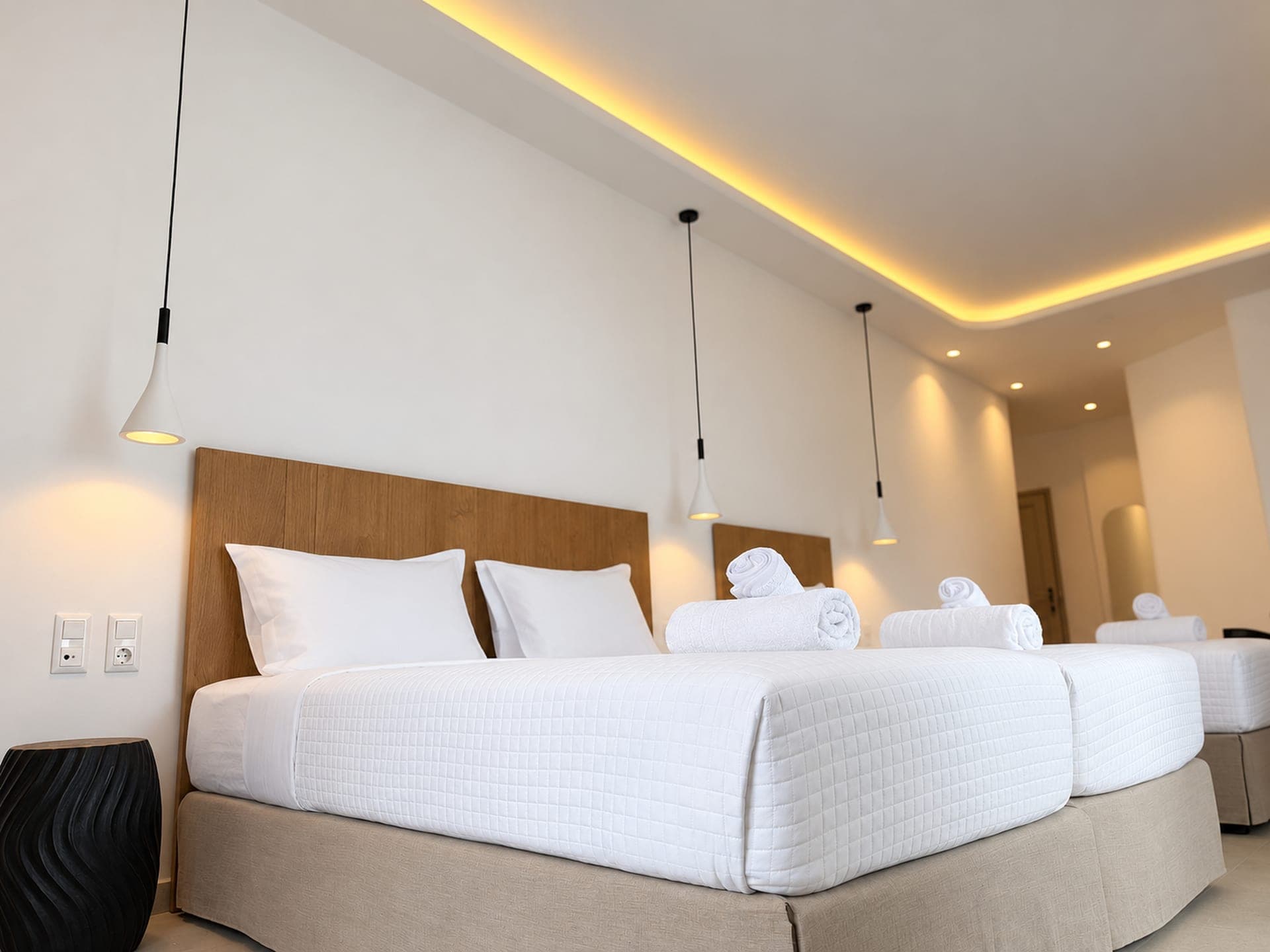 Suite with oak headboards, white bedding and warm cove lighting