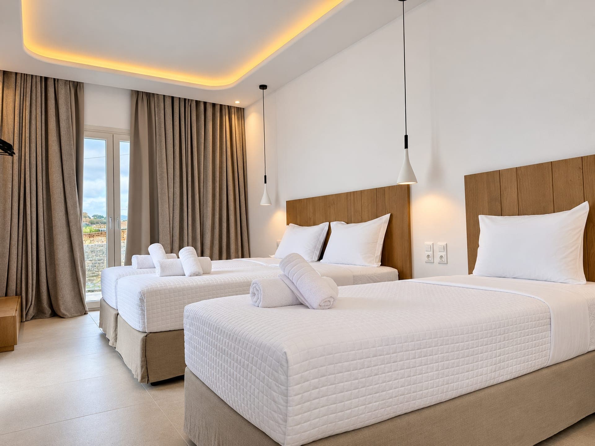 Suite with oak headboards, white bedding and warm cove lighting